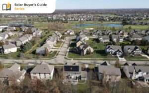 Aerial view of a suburban neighborhood with houses, roads, and green spaces. A golf course with a water body is visible in the background. A banner in the top-left corner reads "Solar Buyer's Guide Series.